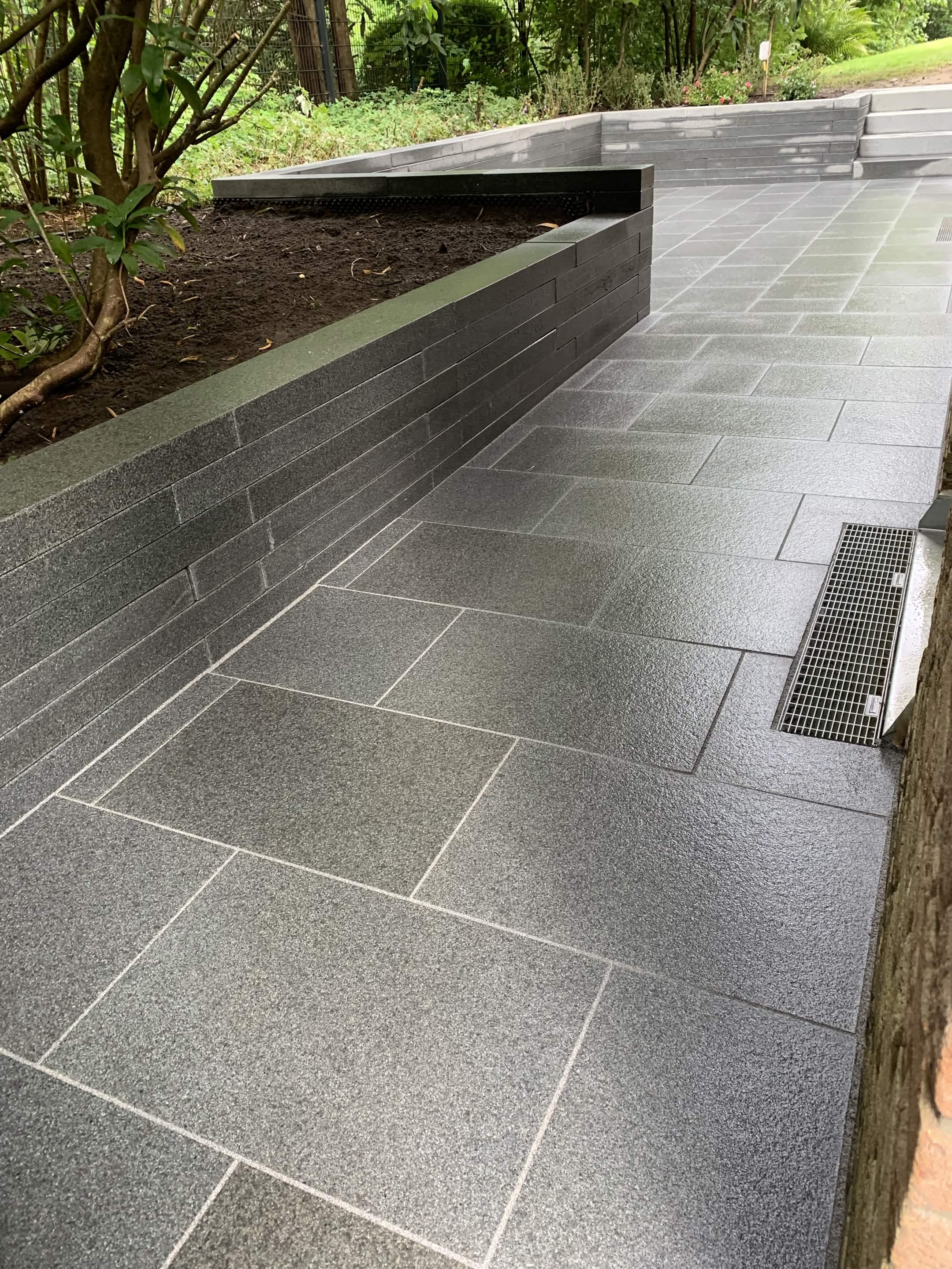 Großformatige Granit-Terrasse mit Natursteinmauer
